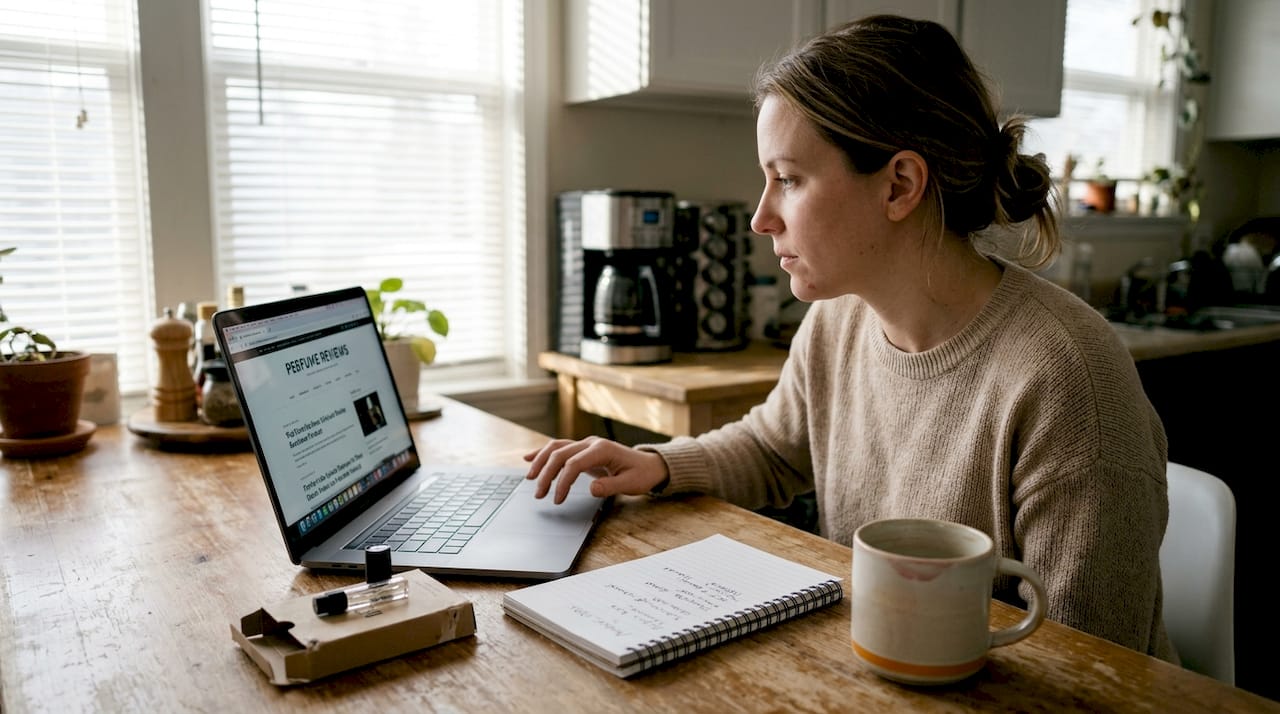 Woman researching perfumes at kitchen table