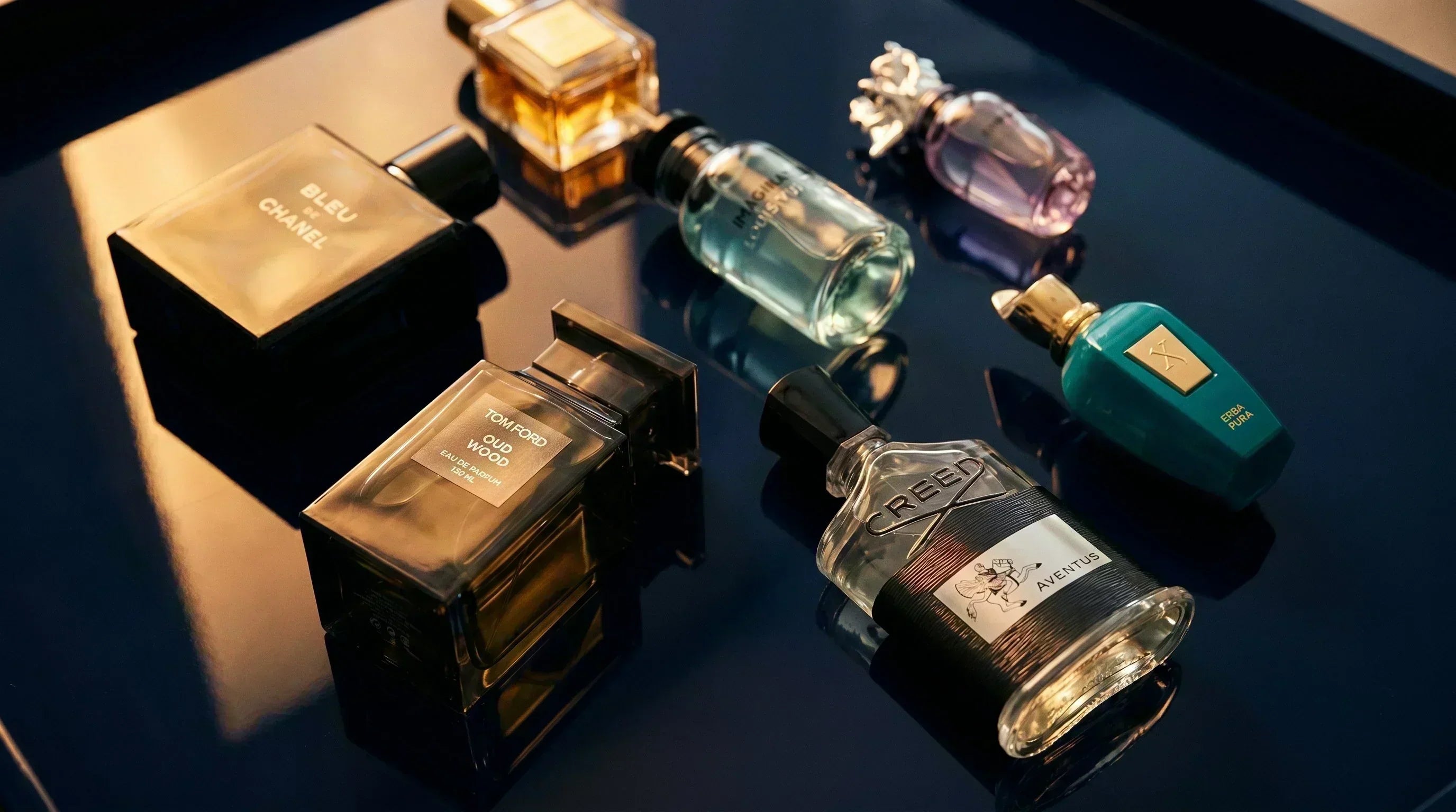 Curated luxury fragrance bottle collection on deep navy velvet with warm amber lighting — Aromatick.com