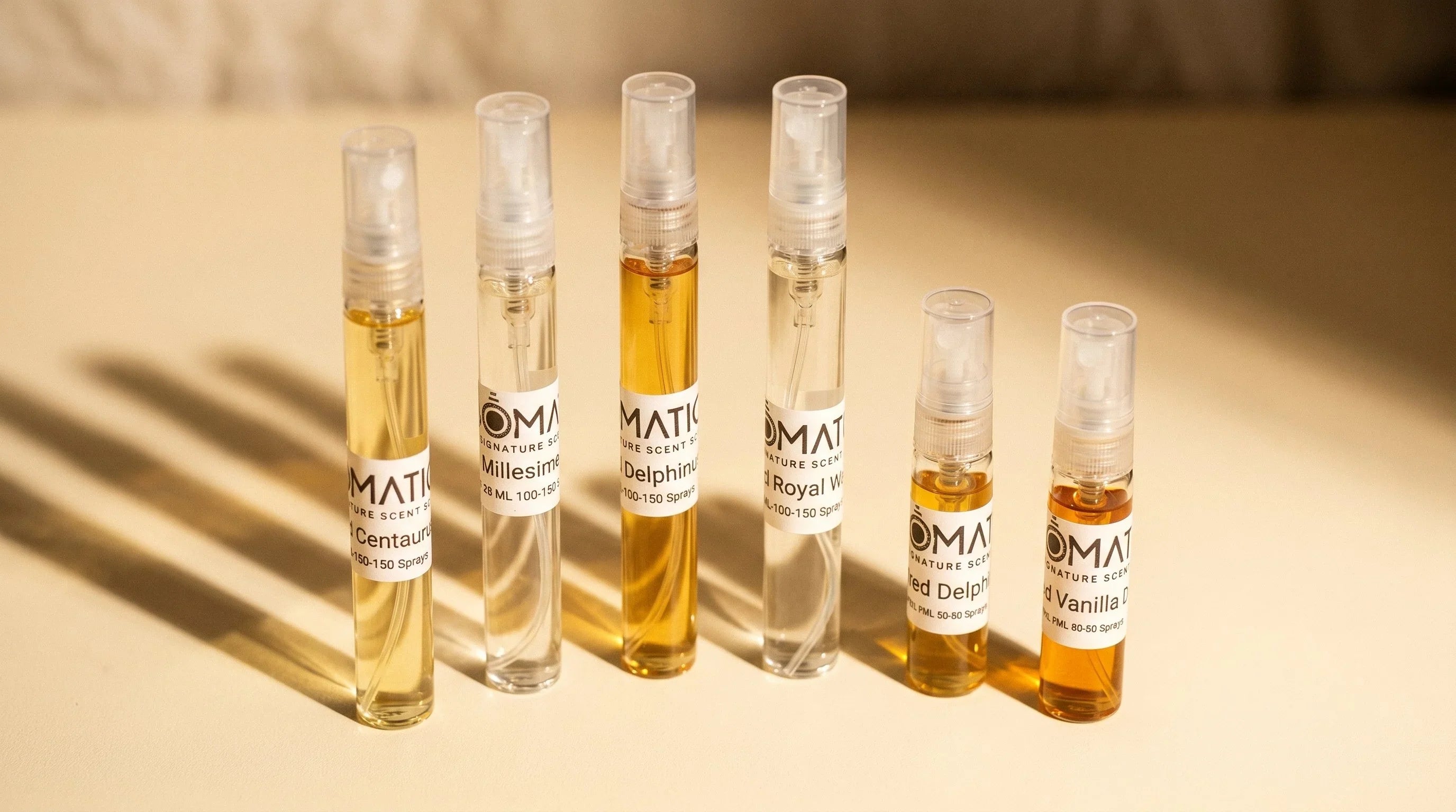Aromatick branded fragrance decant vials arranged on warm cream surface — 10ml and 5ml sizes shown