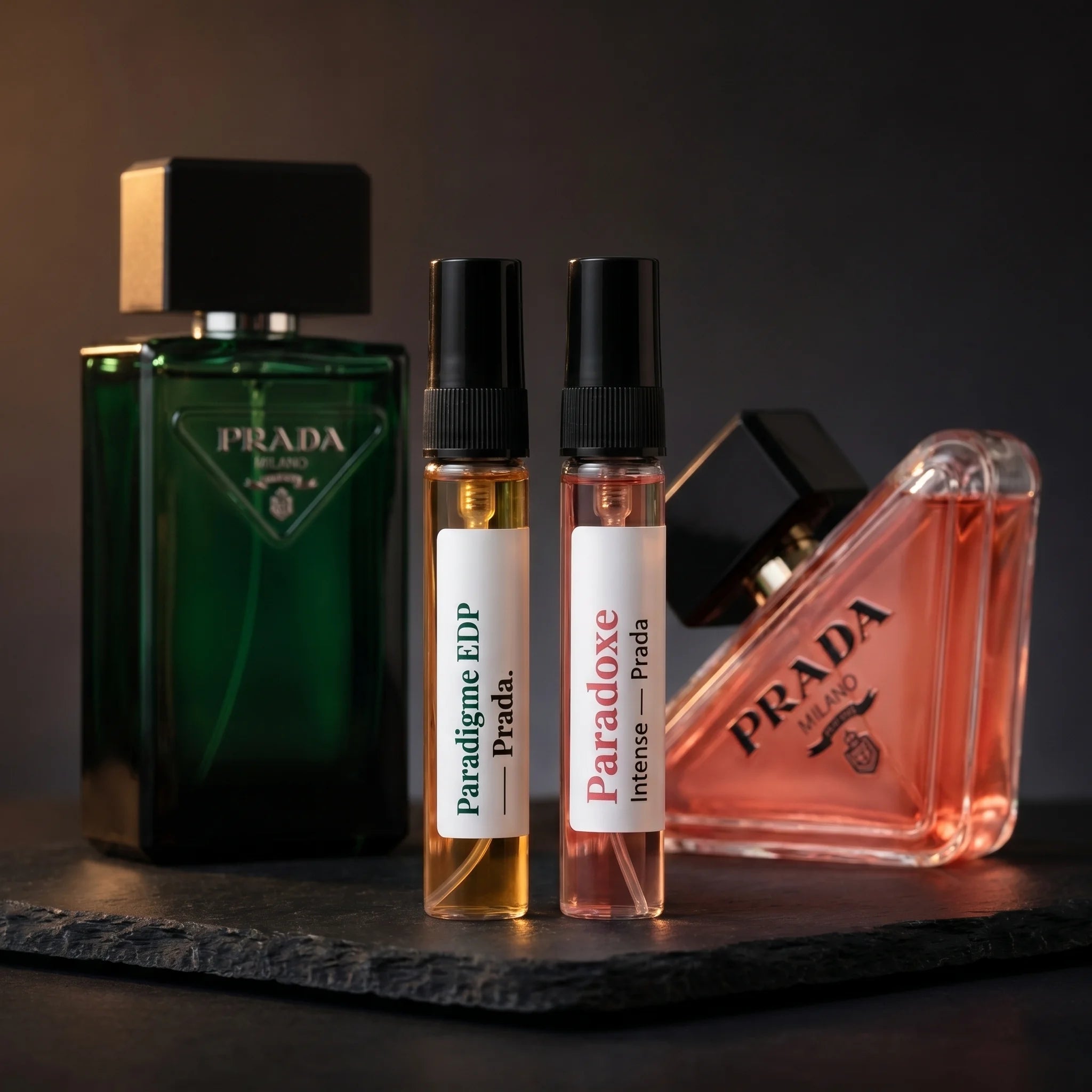 Aromatick Prada Paradigme & Paradoxe Intense His & Hers Discovery Set — two 5ml decants with the dark emerald Paradigme bottle and coral pink Paradoxe Intense bottle on dark slate
