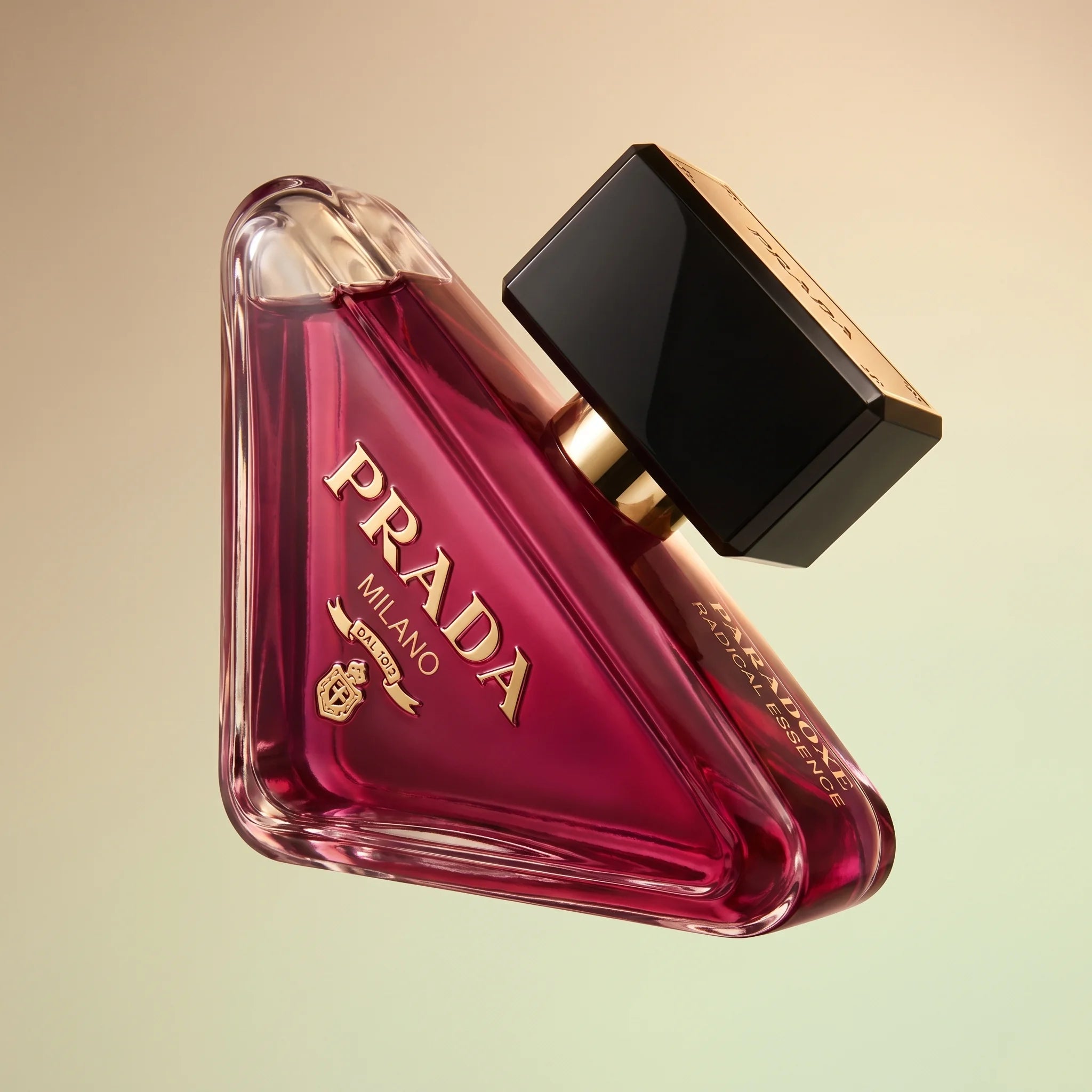Prada Paradoxe Radical Essence Parfum bottle at three-quarter angle showing faceted glass on a pale pistachio gradient