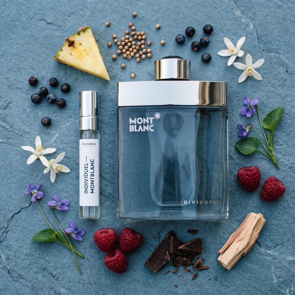 Montblanc Individuel flatlay with pineapple, juniper berries, orange blossom, violets, raspberries and dark chocolate