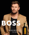 Man in a tan jacket with 'BOSS' branding and a bottle of BOSS bottled on a black background
