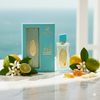 Perfume bottle with packaging and citrus fruits on a light surface