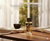 Bottle of cologne on a table with a cup and book, text 'Where elegance meets simplicity'.