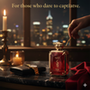 Red perfume bottle with gold cap on a dark surface with candles and cityscape in the background