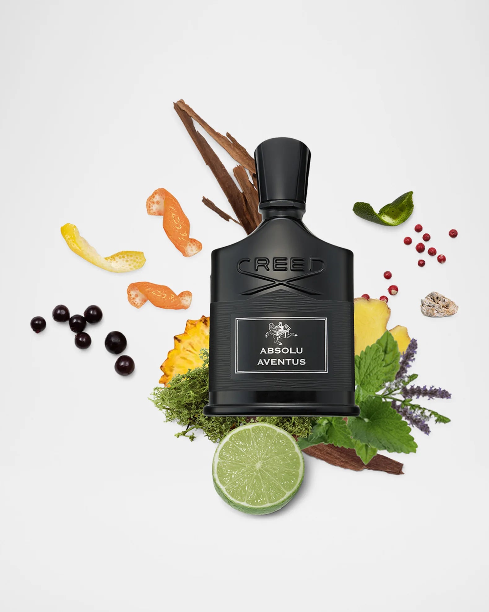 Black Creed perfume bottle surrounded by fruits, leaves, and spices on a white background