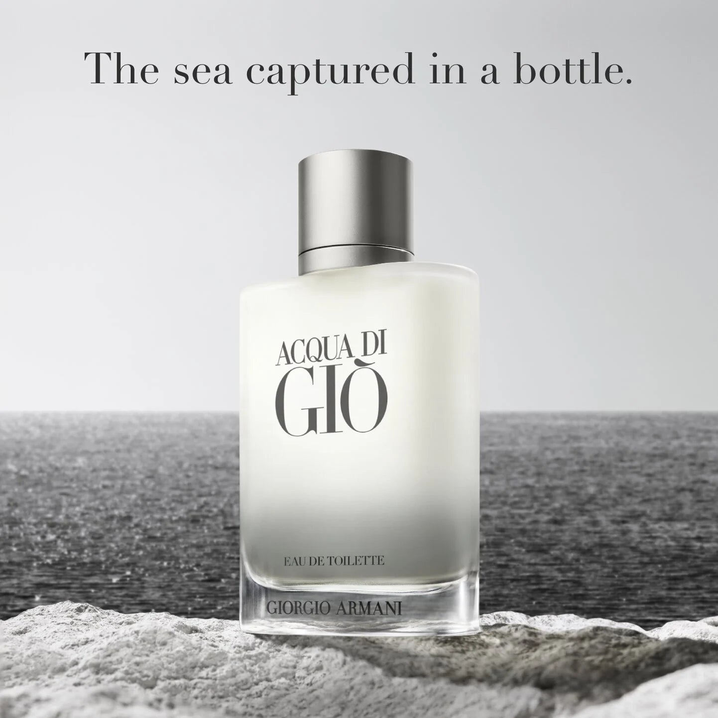 Perfume bottle labeled 'Acqua di Giò' by Giorgio Armani with a coastal background.