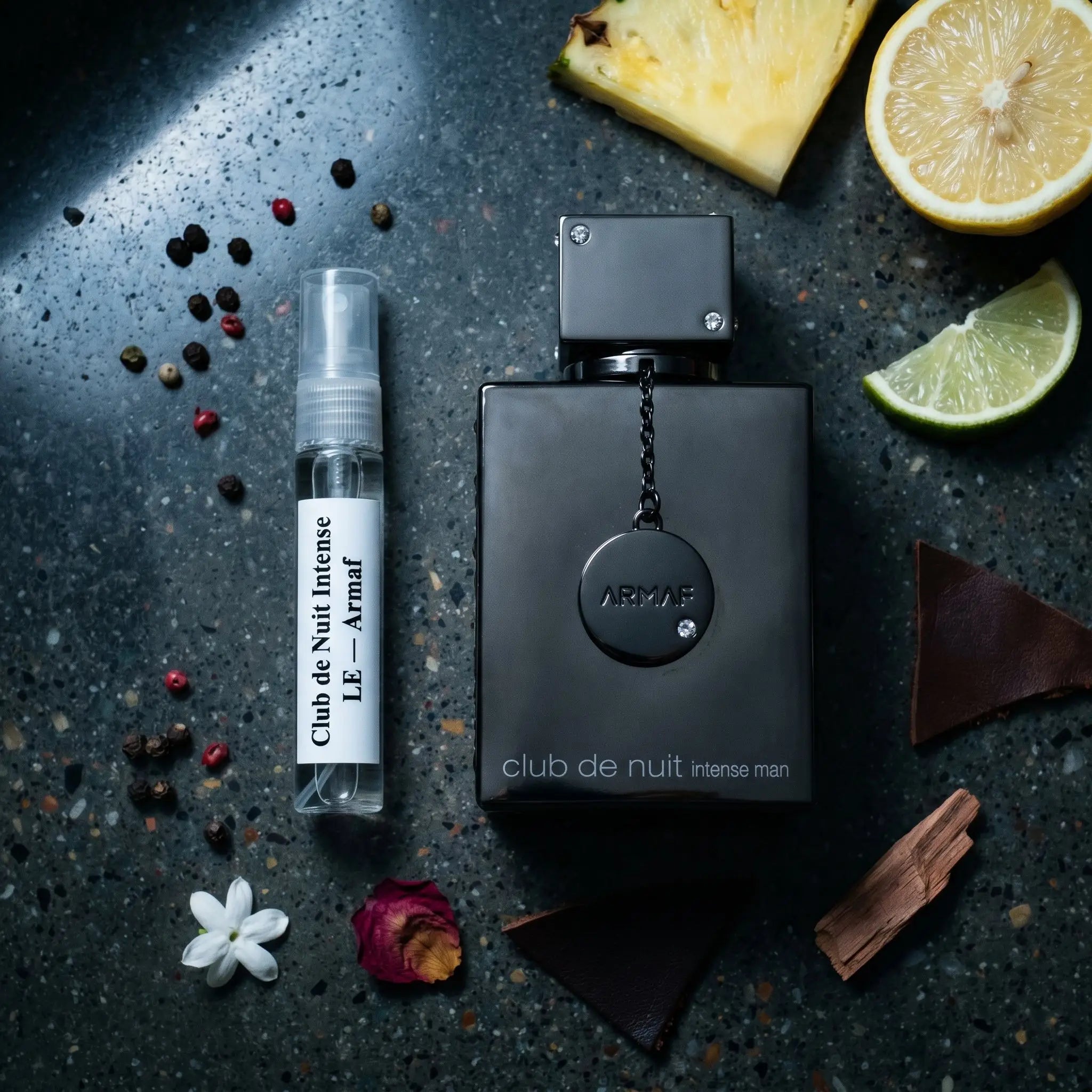 Armaf Club de Nuit Intense Man LE bottle and decant on dark granite with pineapple lemon jasmine leather cedar ambergris fragrance notes flatlay