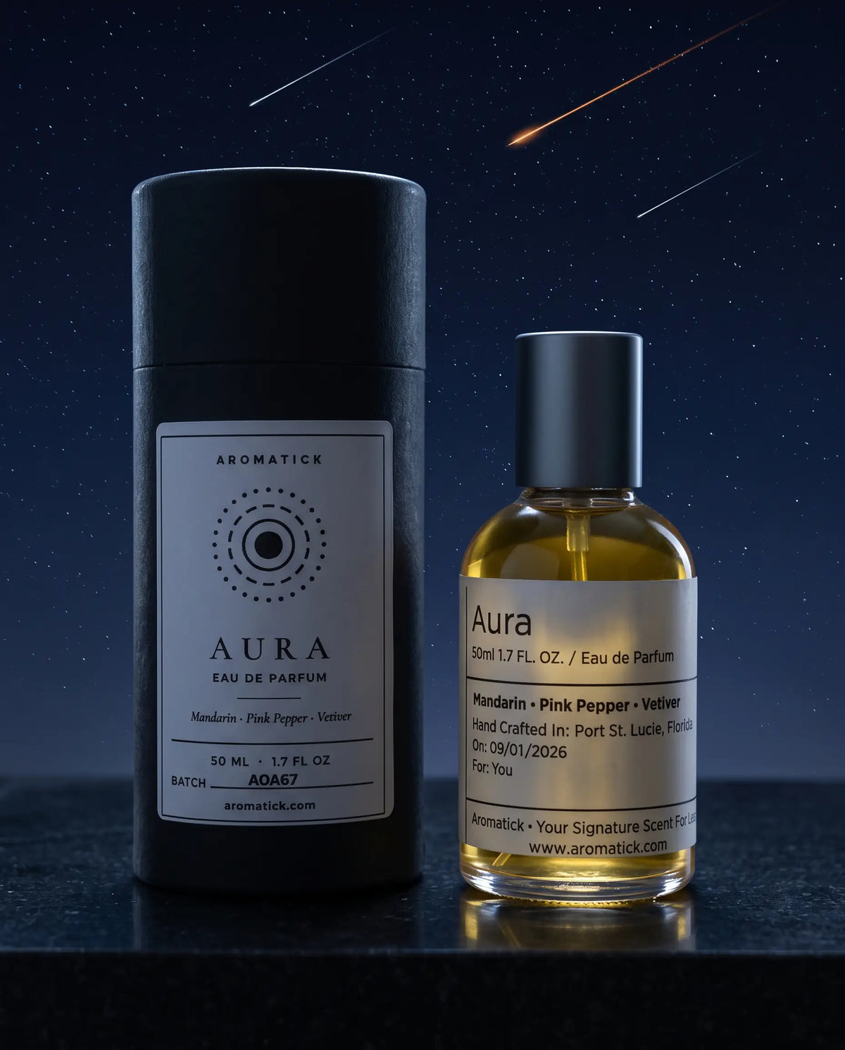 Aromatick Aura 50ml eau de parfum bottle beside its black gift tube under a night sky with shooting stars.
