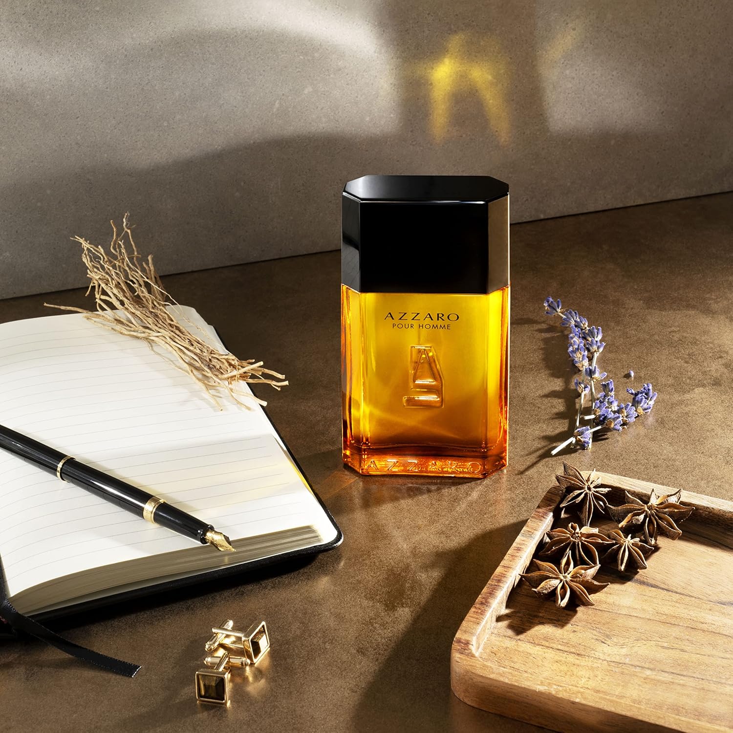 Azzaro perfume bottle on a wooden surface with a notebook and decorative items.