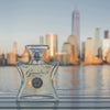 Clear glass perfume bottle with 'Beneday' branding against a city skyline backdrop