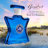 Blue Bond No. 9 Hamptons perfume bottle on a beach with a scenic background