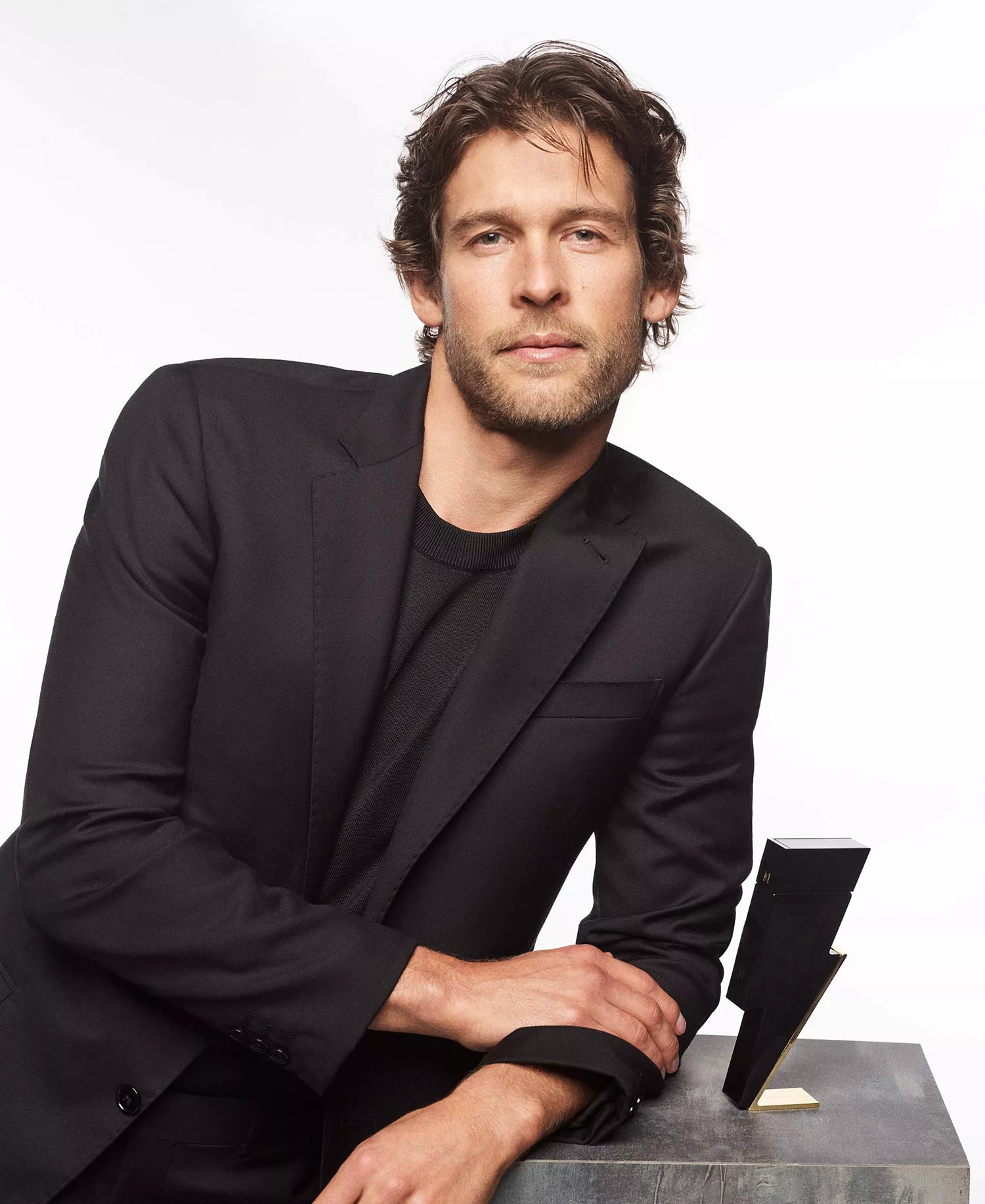 Man in a black suit sitting on a stone block with a white background