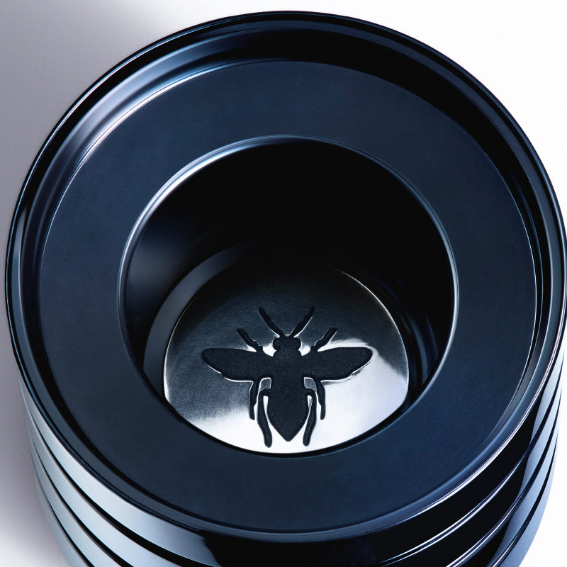 Stack of black plastic containers with a bee logo on a white background