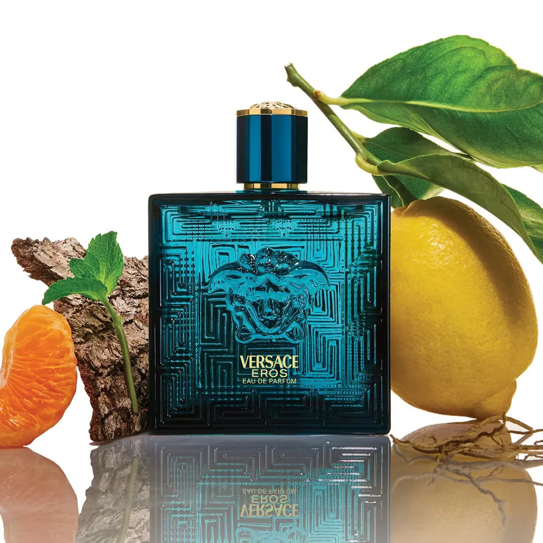 Versace Eros perfume bottle with lemons and leaves on a reflective surface