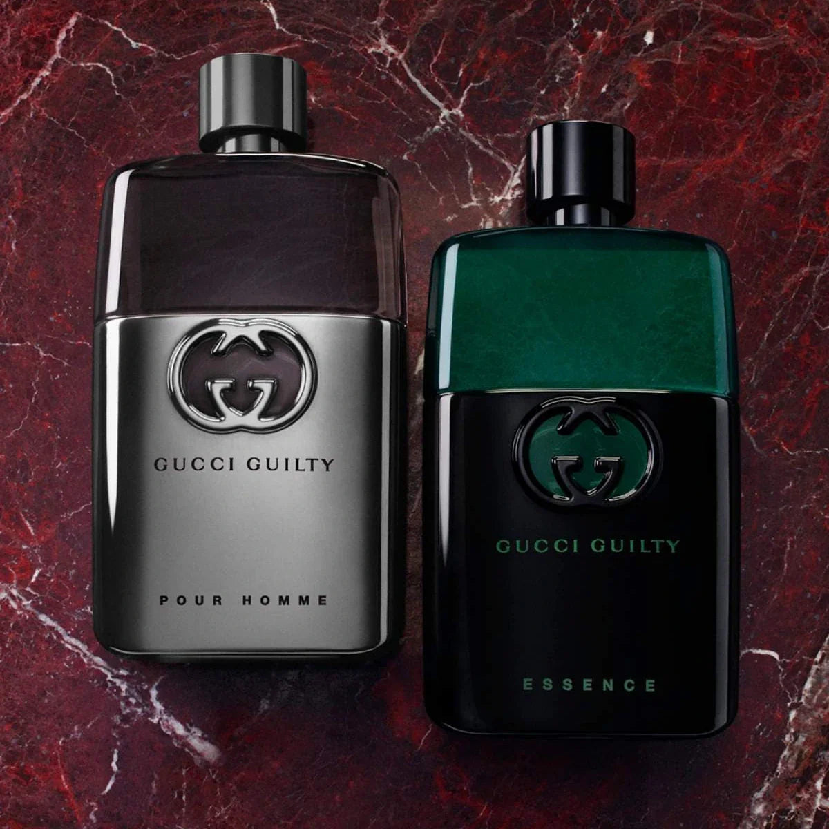 Two Gucci Guilty perfume bottles on a marbled red and black background