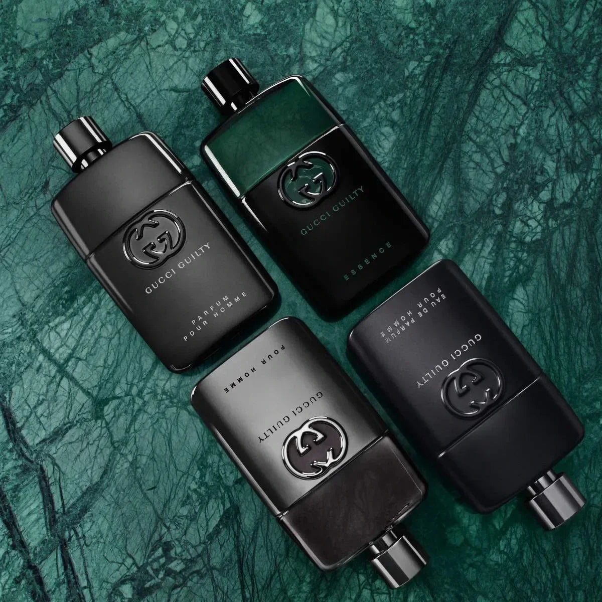Four black Gucci quality perfume bottles on a textured green background