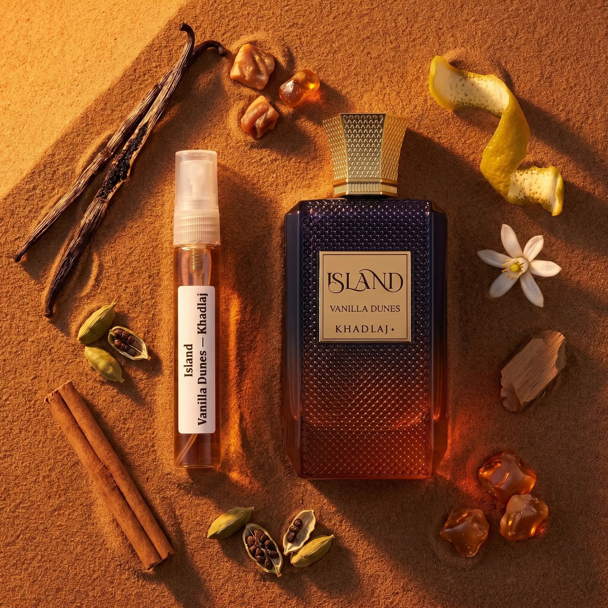 Khadlaj Vanilla Dunes bottle and decant on desert sand with vanilla cinnamon cardamom orange blossom praline amber fragrance notes flatlay