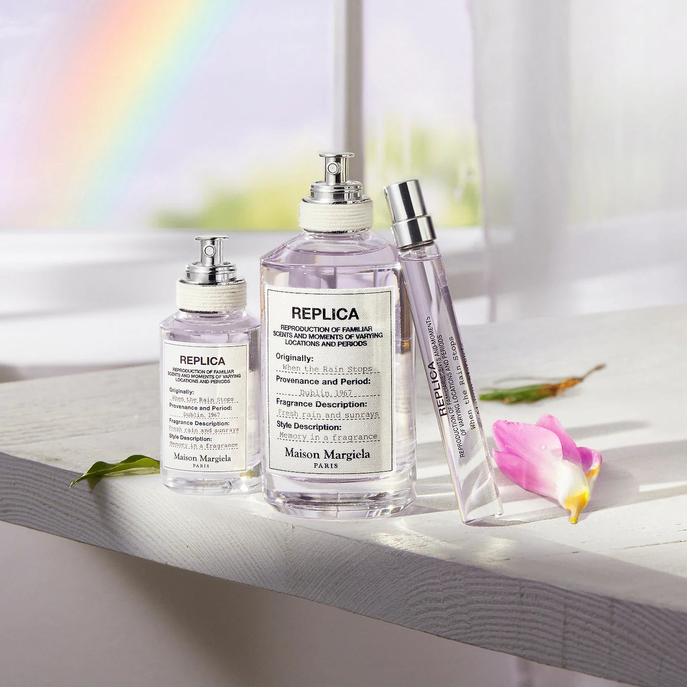 Three perfume bottles on a windowsill with a rainbow in the background
