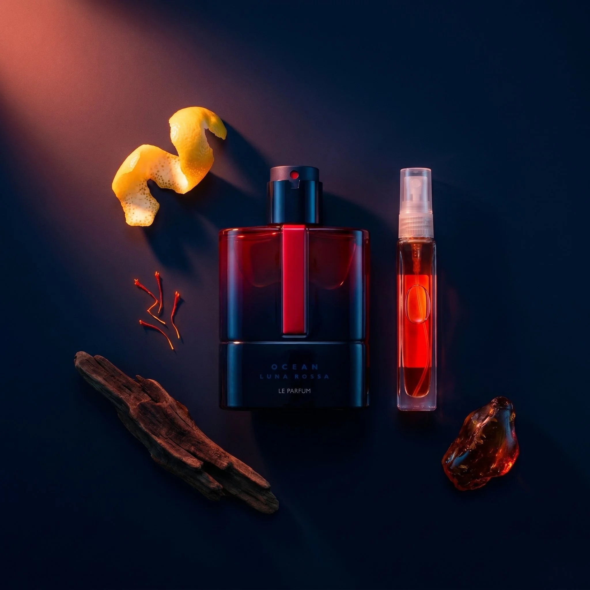 Prada Luna Rossa Ocean Le Parfum bottle and decant on dark navy surface with lemon saffron and oak fragrance notes flatlay