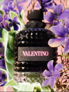 Black Valentino perfume bottle surrounded by purple flowers