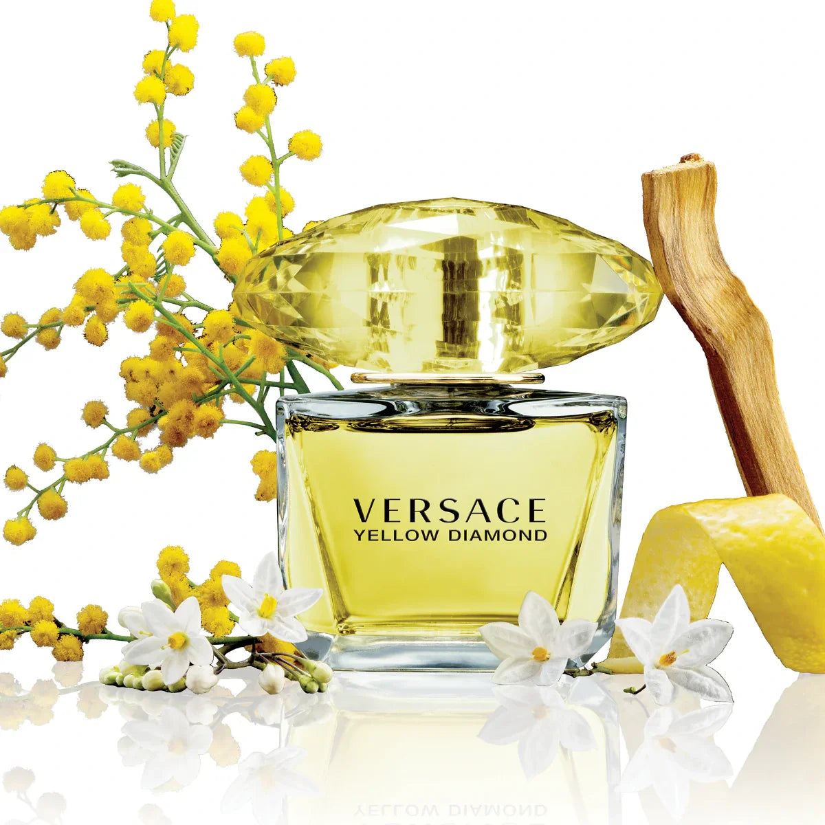 Versace Yellow Diamond perfume bottle with yellow flowers on a reflective surface
