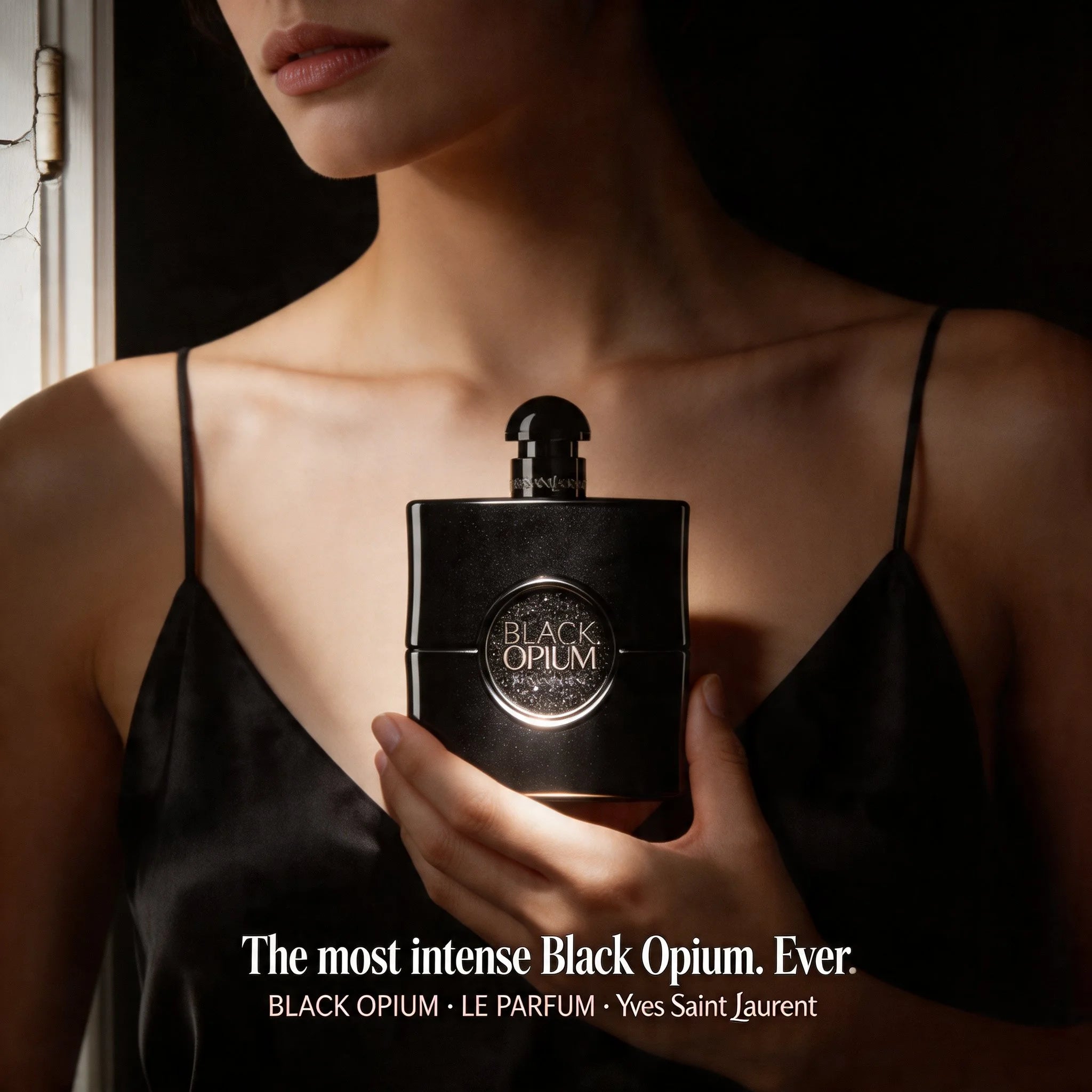 Person holding a Yves Saint Laurent Black Opium perfume bottle.