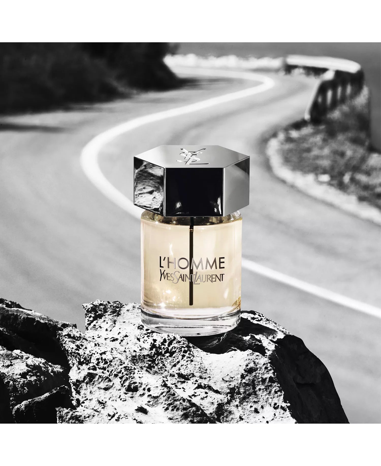 Yves Saint Laurent L'Homme perfume bottle on a rock with a road in the background