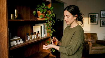 Woman sampling niche perfumes at home shelf