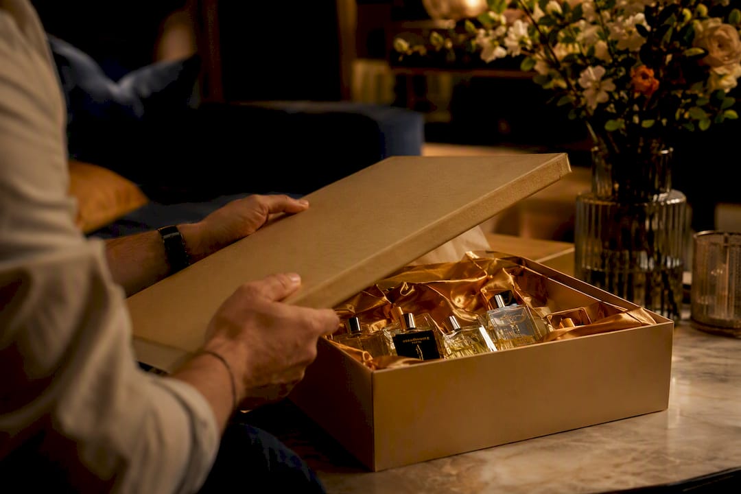 Hands unwrapping a luxury fragrance gift box