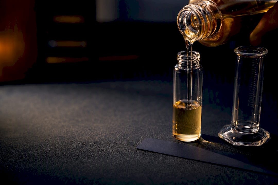 Cropped fragrance bottle beside measured decant vial