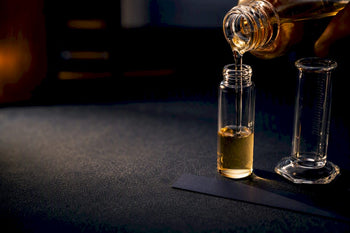 Cropped fragrance bottle beside measured decant vial