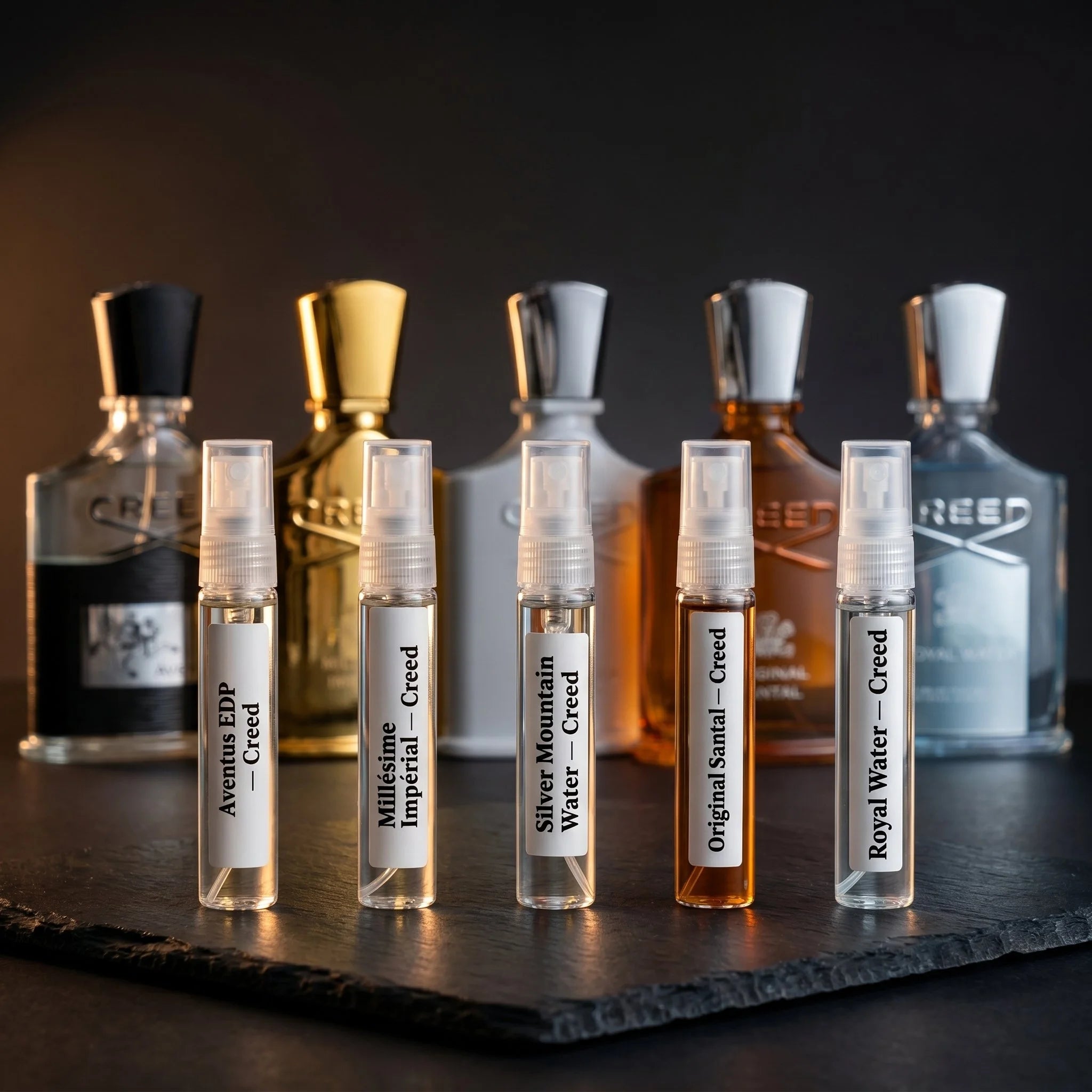 Aromatick Creed Discovery Set — five 5ml decants of Aventus, Millésime Impérial, Silver Mountain Water, Original Santal, and Royal Water with full-size Creed bottles in the background