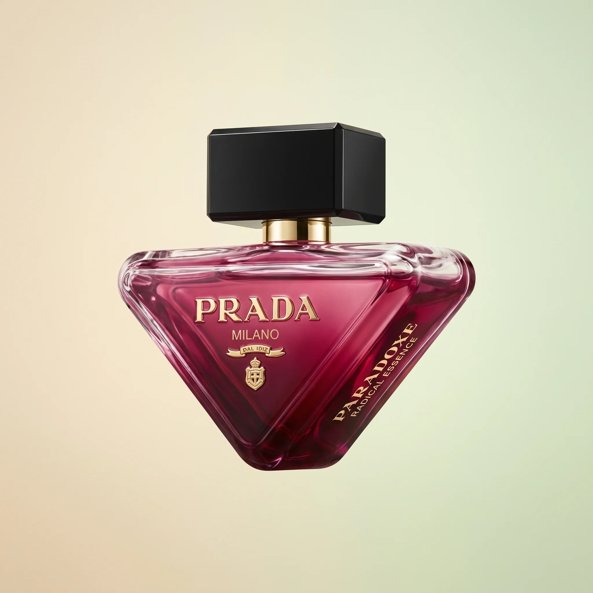 Prada Paradoxe Radical Essence Parfum 3 oz bottle — clear triangular glass with deep magenta juice and gold PRADA logo on a cream-pistachio backdrop
