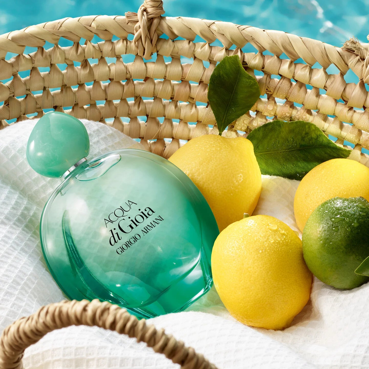 Green bottle of Acqua di Gioia perfume with lemons and limes in a woven basket.