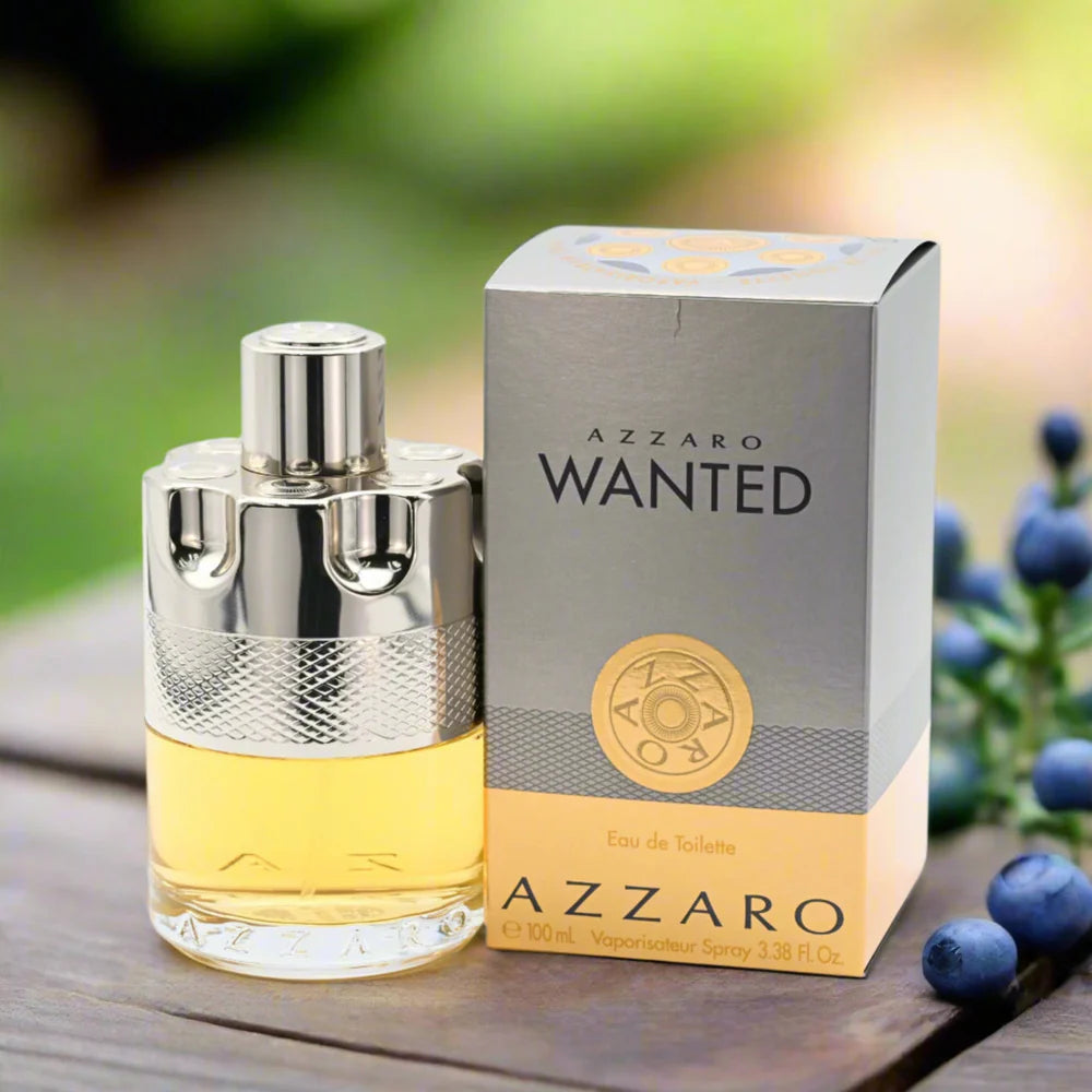 Azzaro Wanted perfume bottle and packaging on a wooden surface with blurred greenery in the background