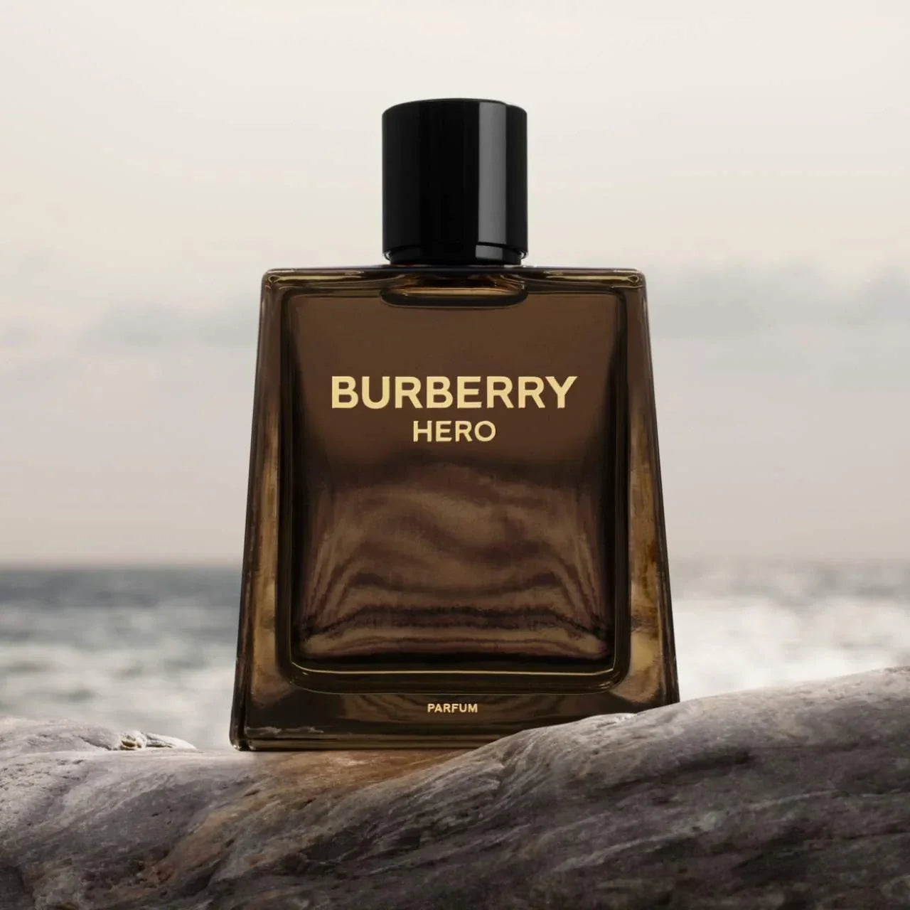 Burberry Hero parfum bottle on a rock with a blurred ocean background