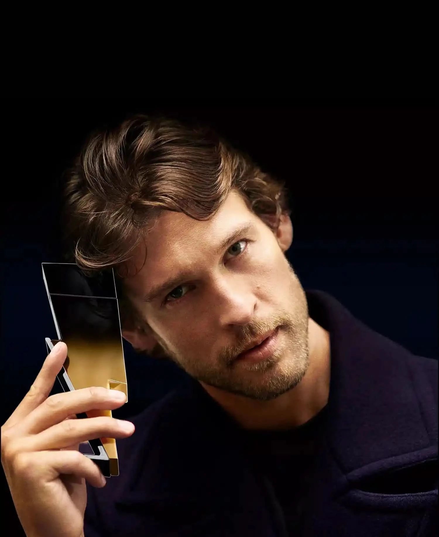 Man holding a smartphone with a reflective screen against a dark background