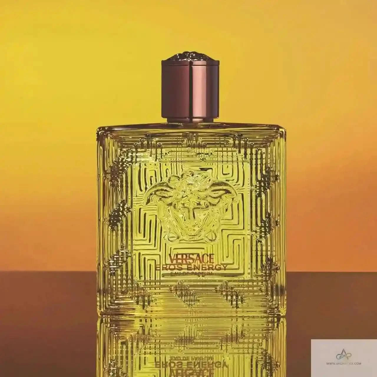 Versace Eros Energy perfume bottle on a gradient yellow to orange background