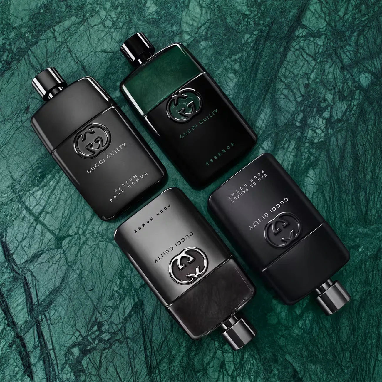 Four black Gucci perfume bottles on a textured green background