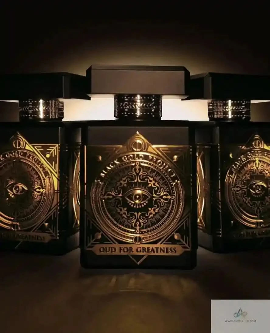 Three Initio Oud For Greatness EDP bottles illuminated in dramatic lighting, emphasizing the bold black and gold luxury design.