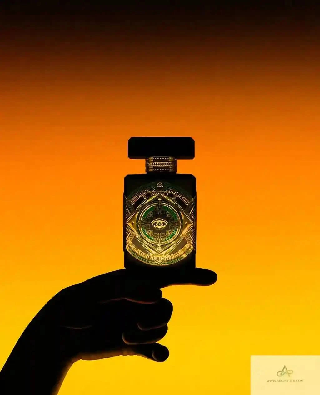 Hand holding a perfume bottle with a glowing label against an orange background