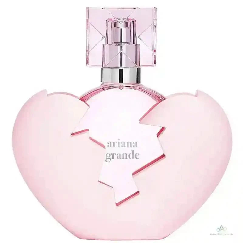 Pink heart-shaped perfume bottle with 'Ariana Grande' branding on a white background
