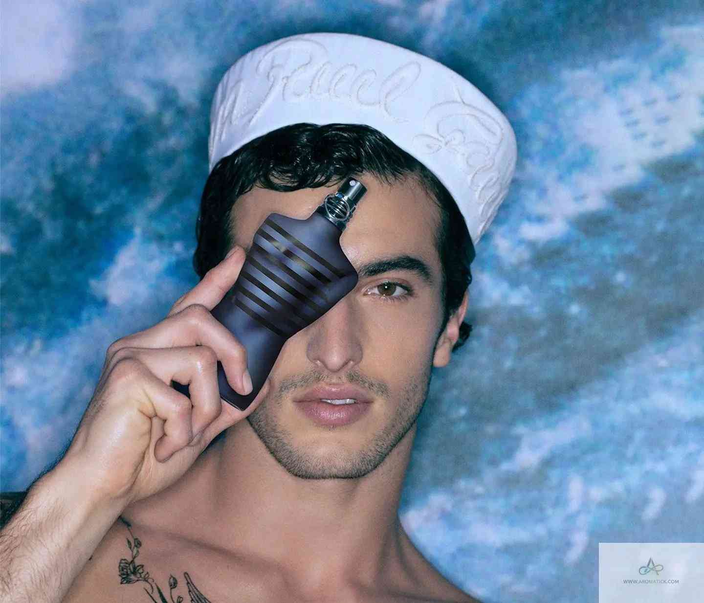 Model holding Ultra Male EDT - Aromatick men's cologne bottle over one eye, showcasing the iconic torso-shaped design.