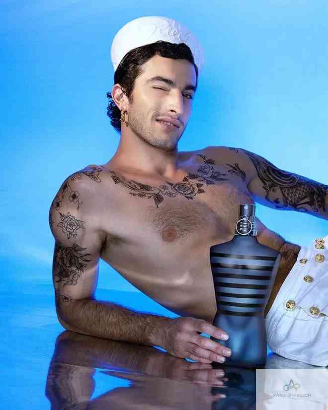 Tattooed model reclining with Ultra Male EDT - Aromatick men's cologne, emphasizing the bold and masculine fragrance appeal.