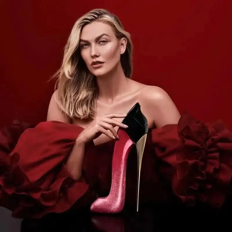 Woman holding a red high-heeled shoe against a red background