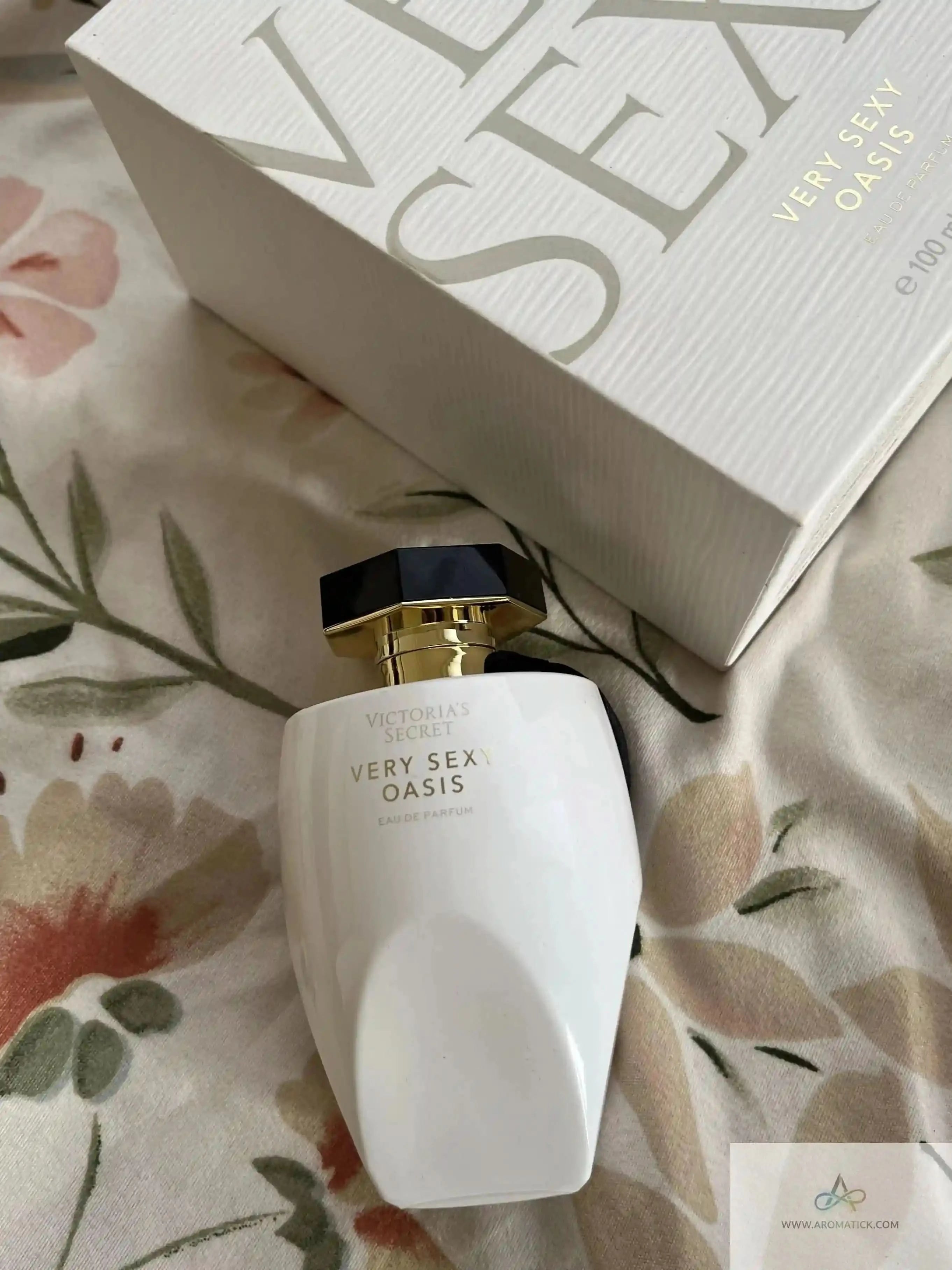 Victoria's Secret 'Very Sex Oasis' perfume bottle and packaging on a floral fabric background