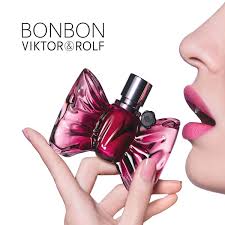 Viktor & Rolf Bonbon perfume bottle with a butterfly design held by a hand, close-up with a white background.