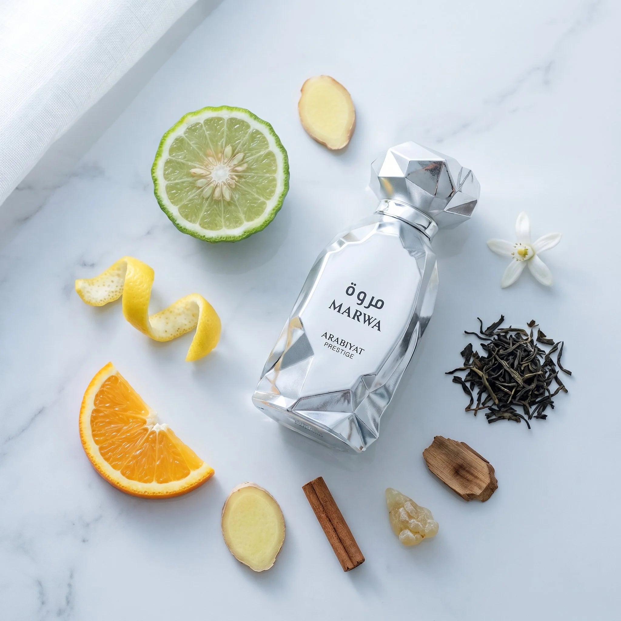 Arabiyat Prestige Marwa EDP flatlay with bergamot, orange, lemon, ginger, cinnamon, neroli, black tea, and guaiac wood on marble

